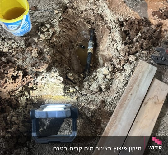 בור באדמה עם צינור מים וכלי עבודה